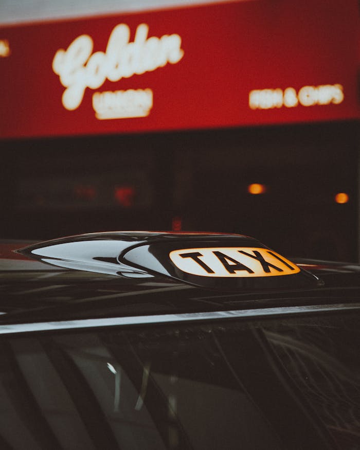 Close-up of a taxi with illuminated roof sign in front of a city restaurant at night.